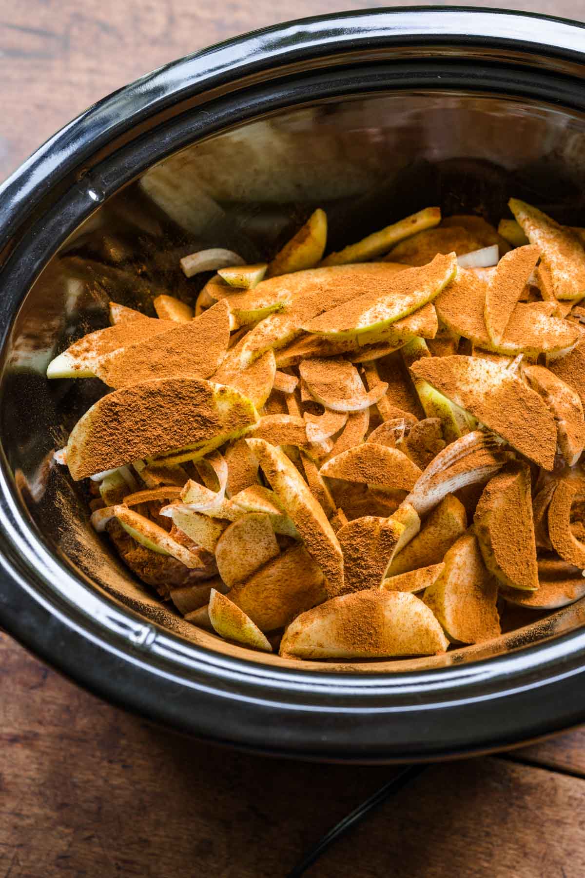 Apple Cinnamon Pork Loin in slow cooker with apple slices and cinnamon on top