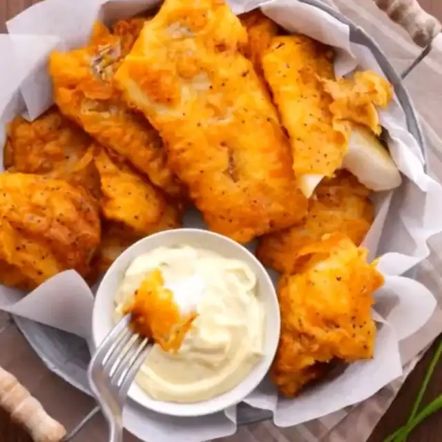 fish in batter on a serving plate with a side of tartar