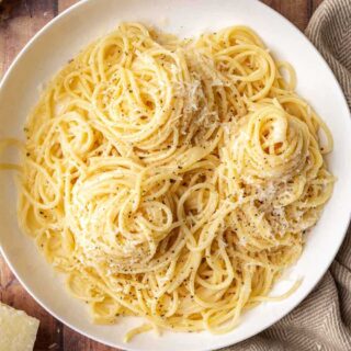 Plate of spaghetti with Romano, Parmesan, and black pepper.
