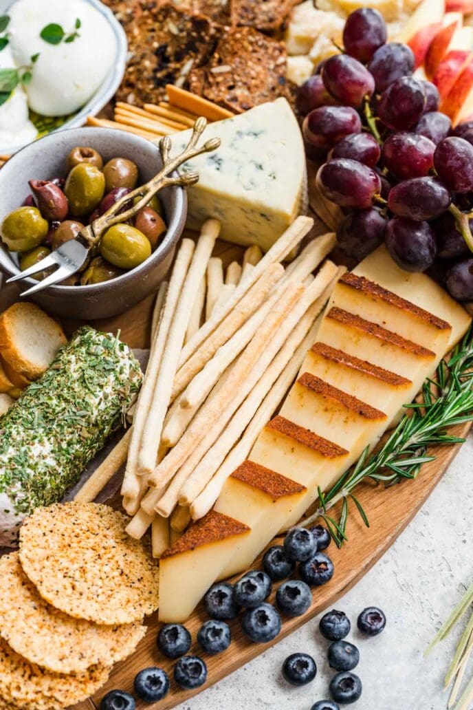 Cheese Board with crackers and accompaniments on round wood board.
