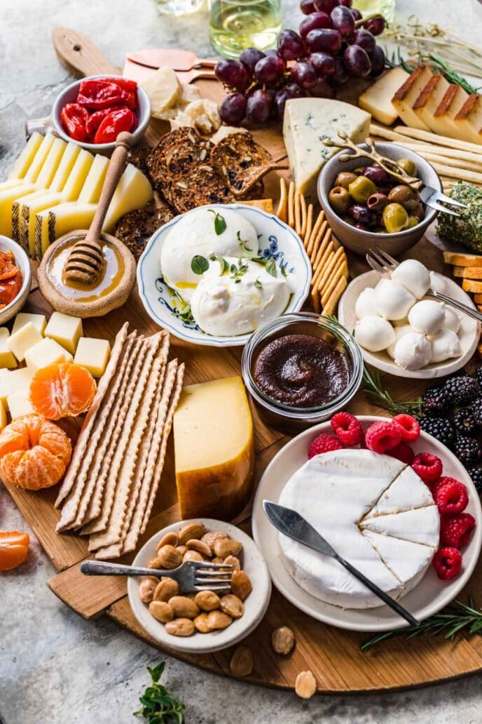 Cheese Board with crackers and accompaniments on round wood board.