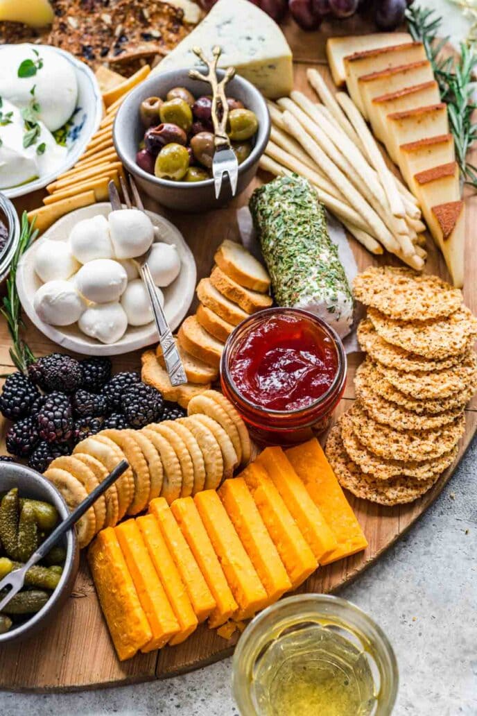 Cheese Board with crackers and accompaniments on round wood board.