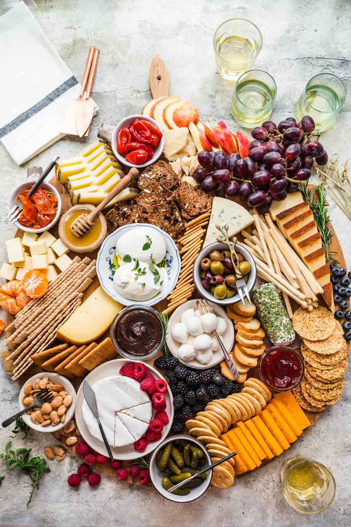 Cheese Board with crackers and accompaniments on round wood board.