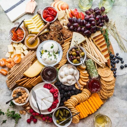 Cheese Board with crackers and accompaniments on round wood board.