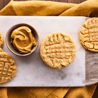 cookies on serving board with cup of peanut butter