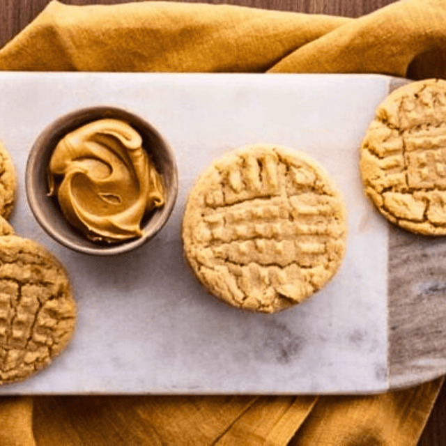 cookies on serving board with cup of peanut butter