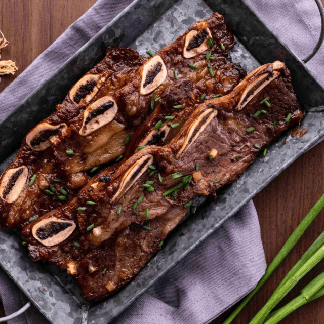 Cooked ribs on serving tray with green onions around tray.