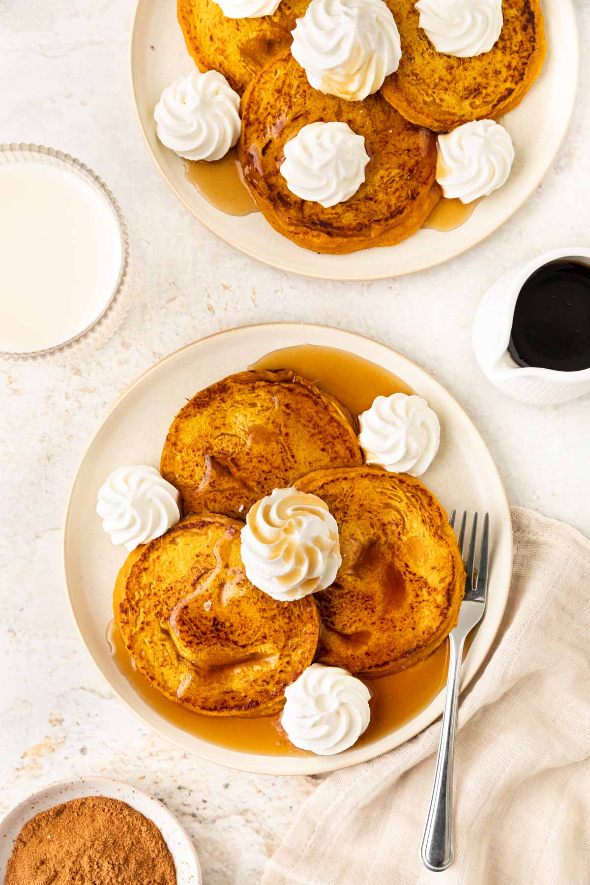 Pumpkin Pancakes three pancakes on plate with whipped cream and syrup