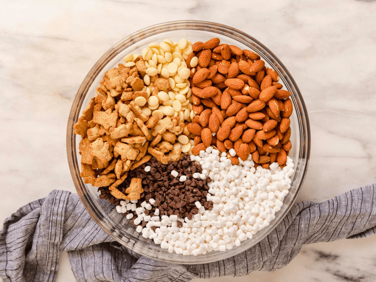 nuts, marshmallows, cookies, and chocolate unmixed in a glass bowl