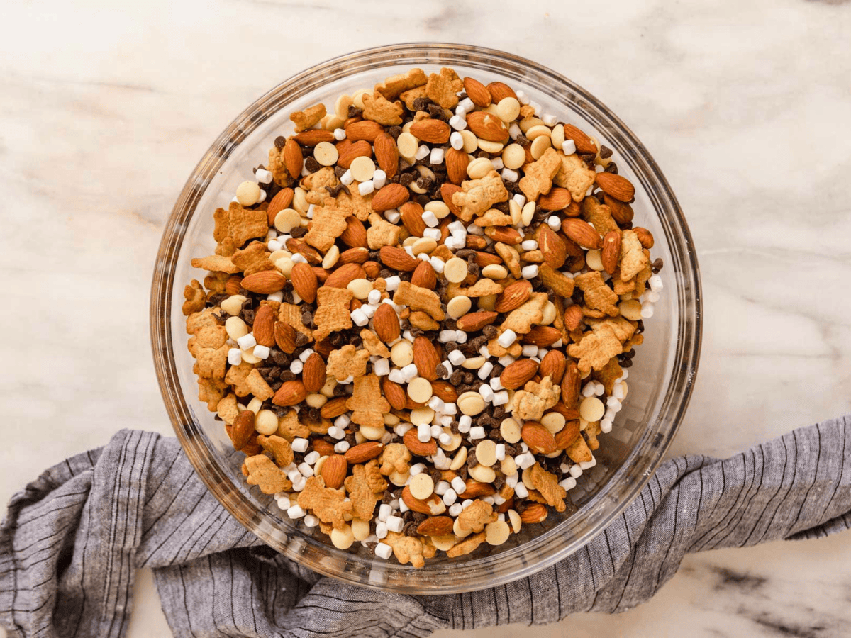 nuts, marshmallows, cookies, and chocolate mixed in a glass bowl