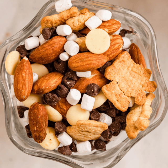 close up of nuts, marshmallows, cookies, and chocolate mixed in a glass bowl