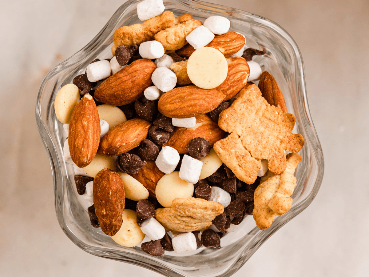 close up of nuts, marshmallows, cookies, and chocolate mixed in a glass bowl