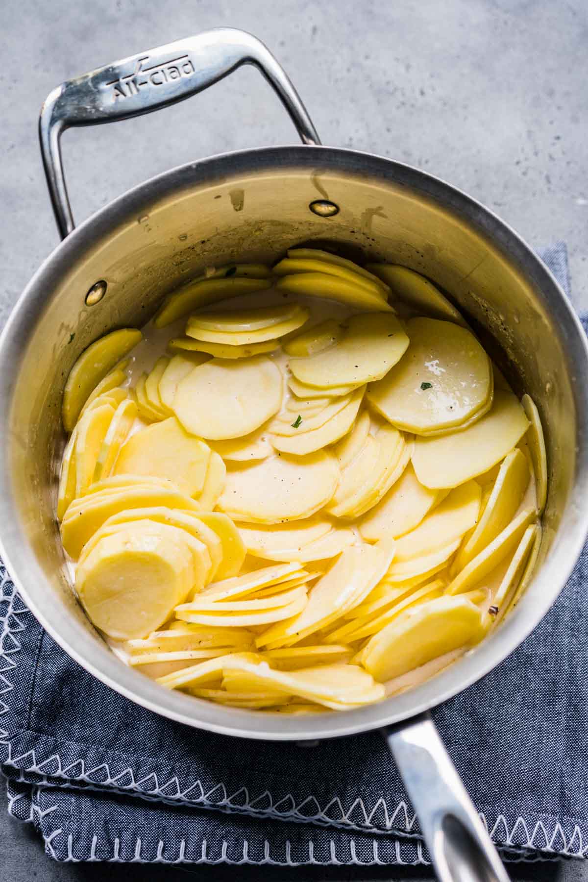 Sheet Pan Scalloped Potatoes sliced potatoes and cream mixture in sauce pan