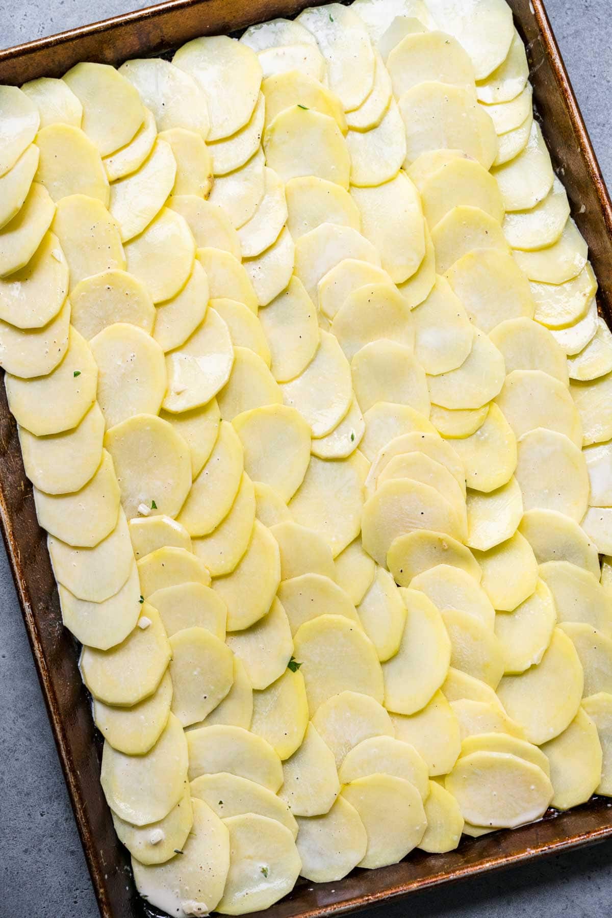 Sheet Pan Scalloped Potatoes sliced potatoes and cream mixture on sheet pan