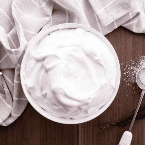 cream in a bowl with mixing paddle and powdered sugar on the side