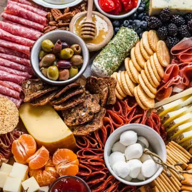 Platter with marinated vegetables, nuts, fruit, cheese, and meat.