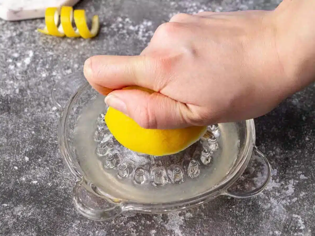 Half a lemon being juiced by hand.