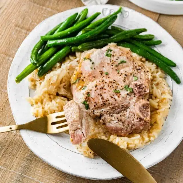 Baked Pork Chops and Rice finished on plate with green beans and bite on fork
