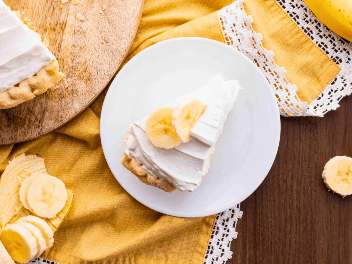 top view of slice of fruit pie with whipped cream on a white plate