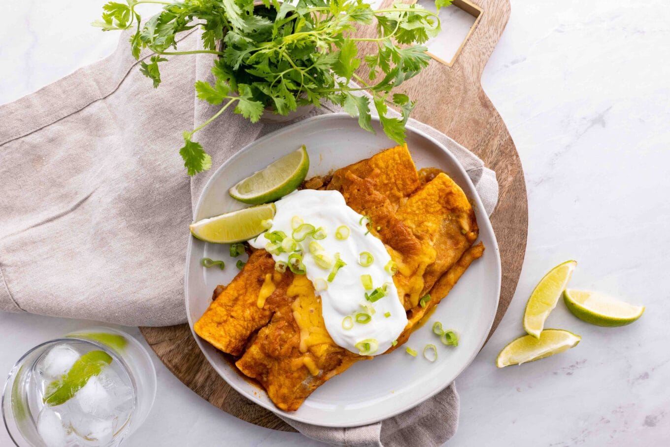 Beef enchiladas on plate topped with sour cream top view