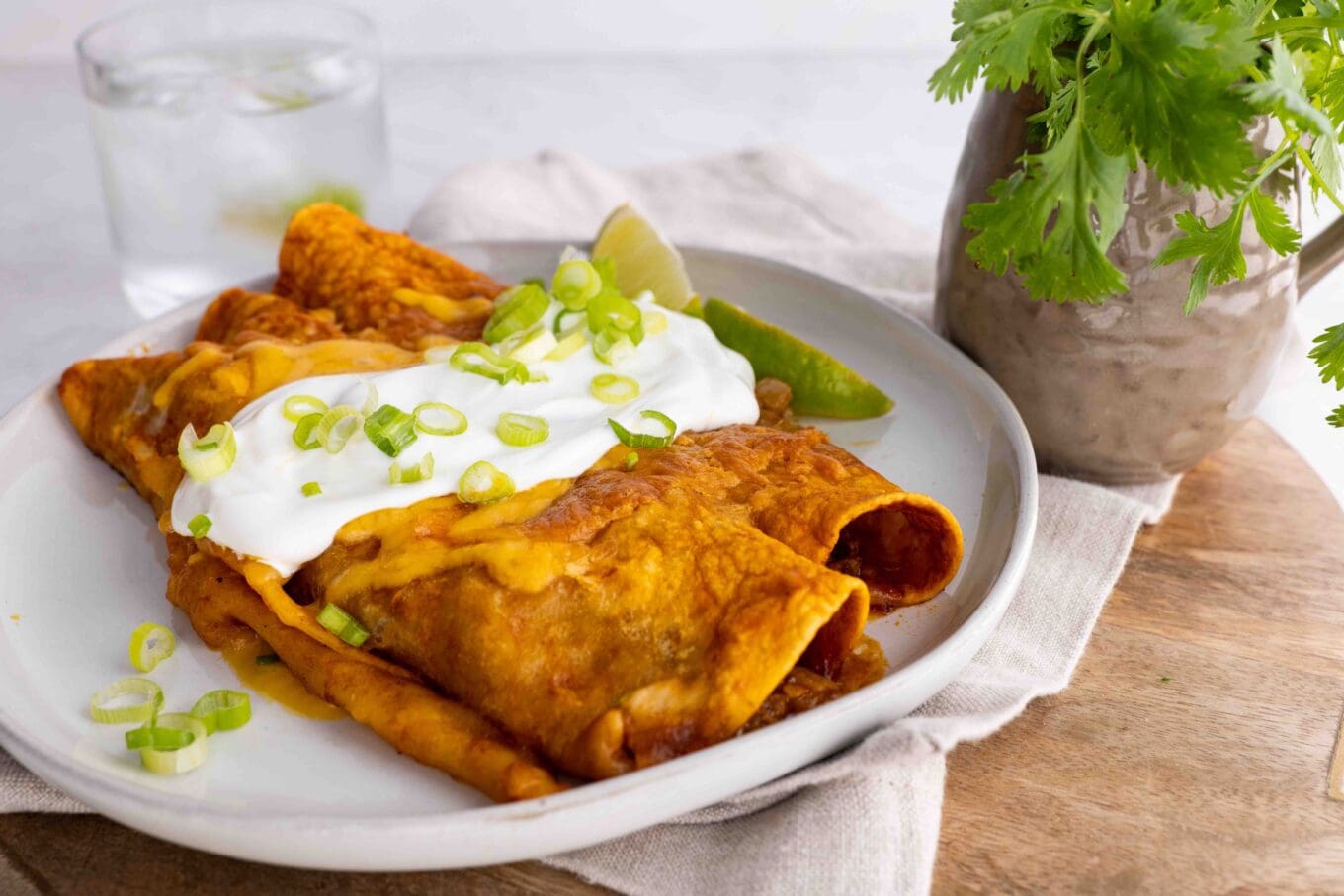 side view Beef enchiladas on plate topped with sour cream