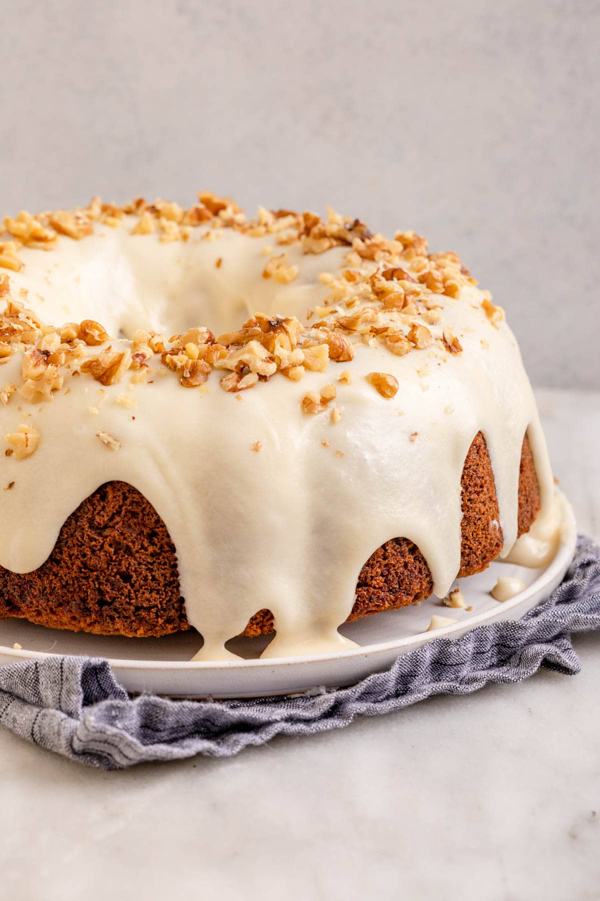 Carrot Bundt Cake on cake platter with icing and walnuts