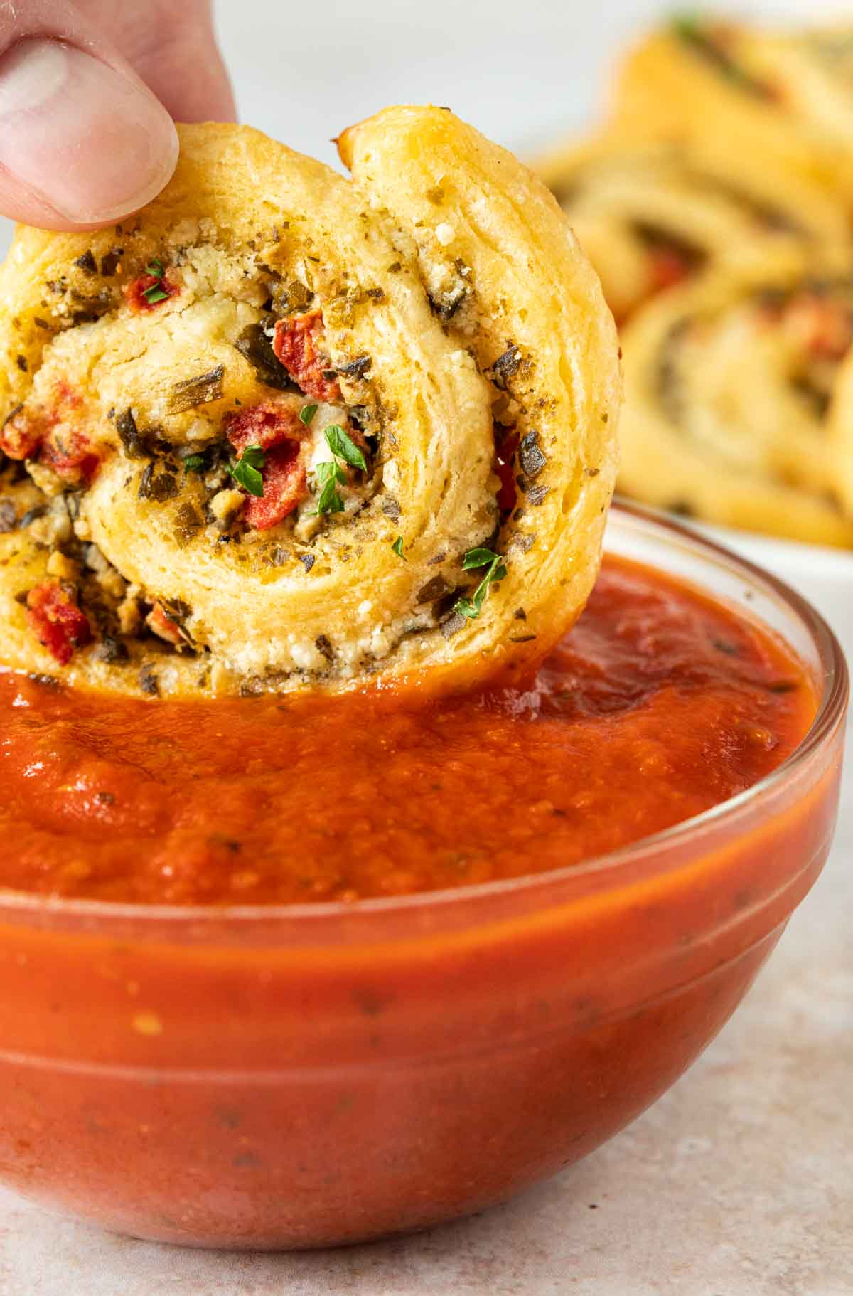 Cheesy Pesto Pinwheels dipping in sauce