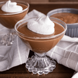 pudding being served in fancy glasses topped with whipped cream