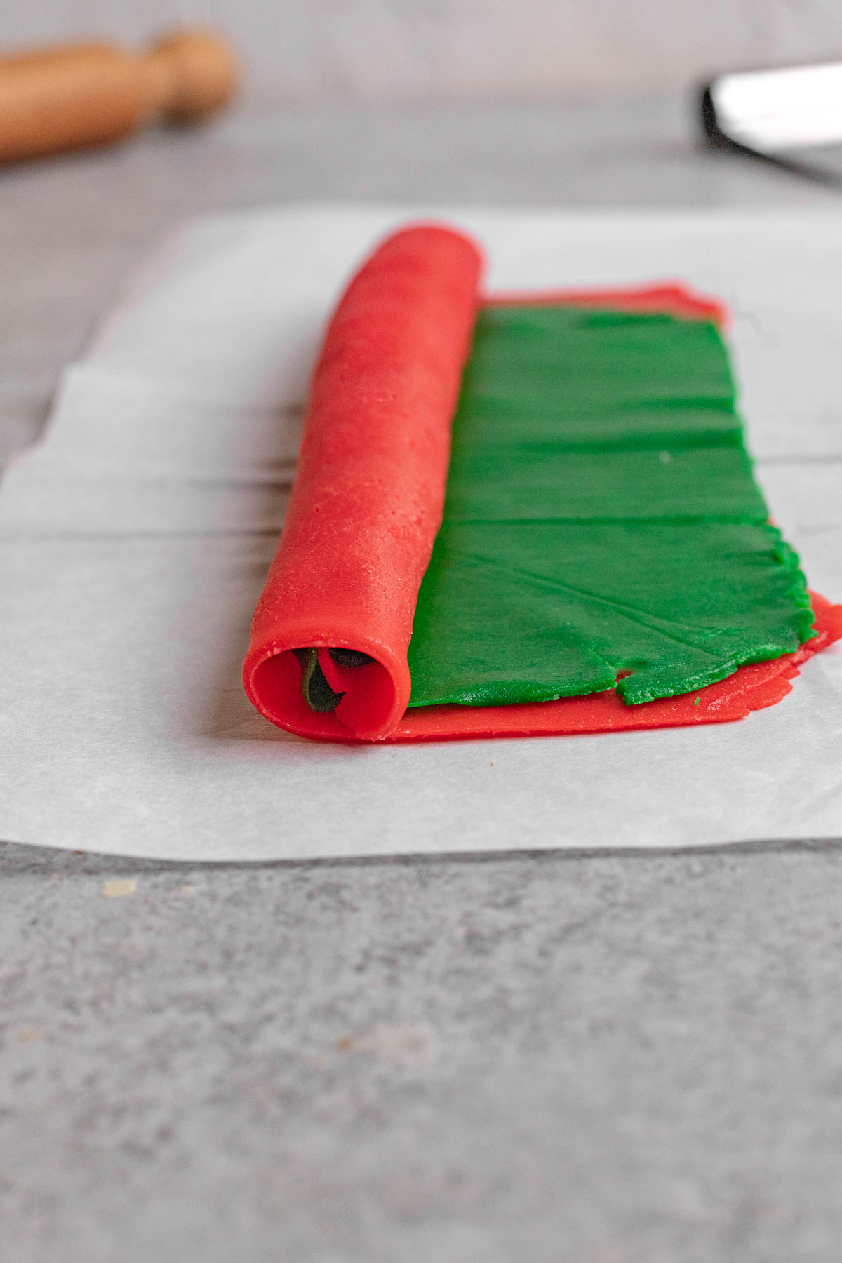 Christmas Pinwheel Cookies green cookie dough sheet on red sheet, rolling up into a dough log