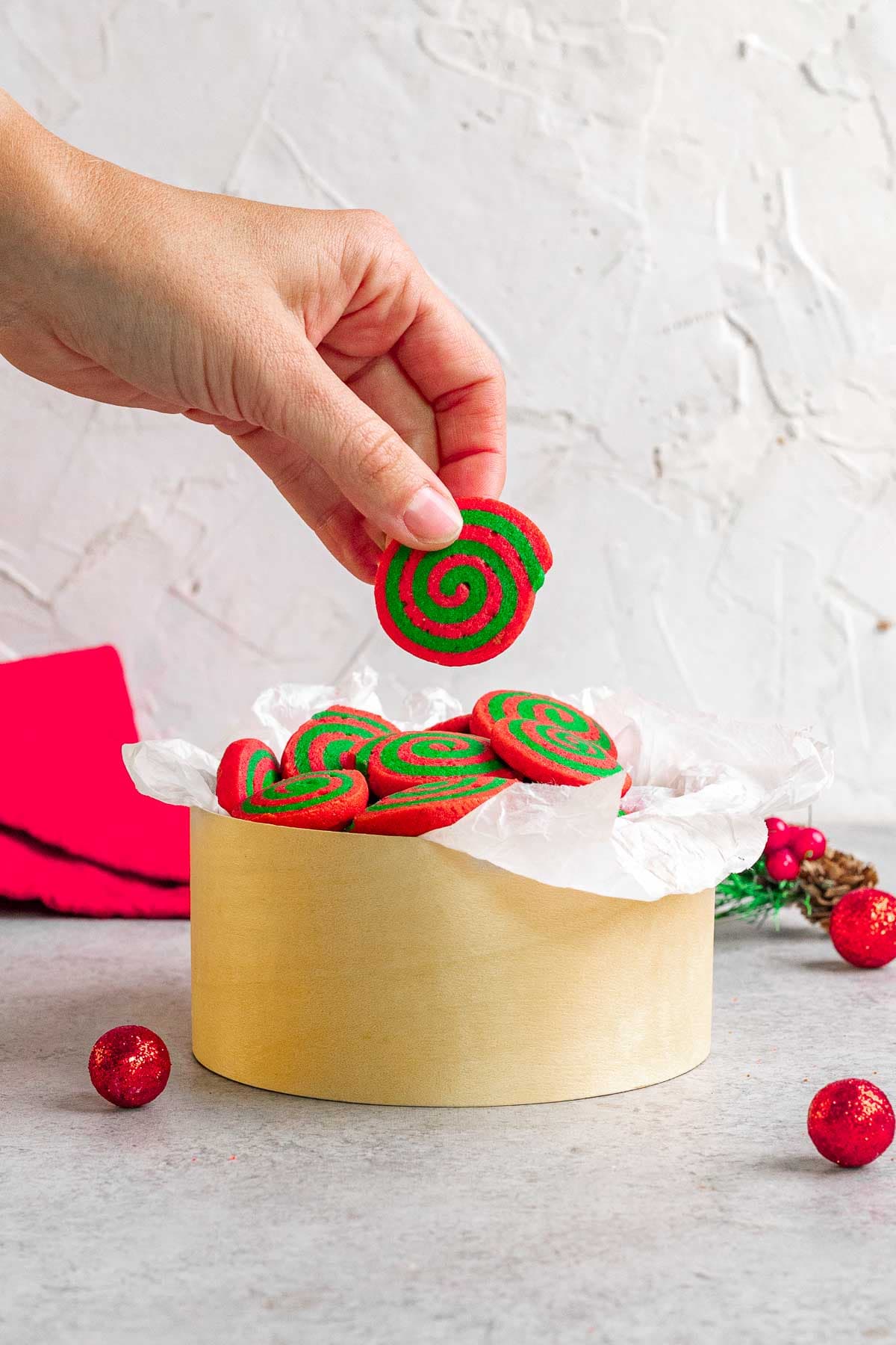 Christmas Pinwheel Cookies in tin with one in hand