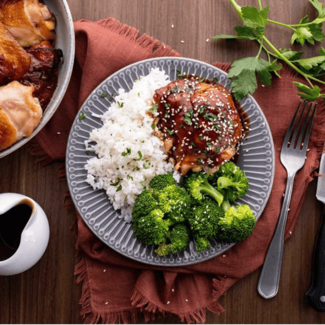 Teriyaki chicken on plate with broccoli and rice. Extra chicken on side of plate with a extra sauce.