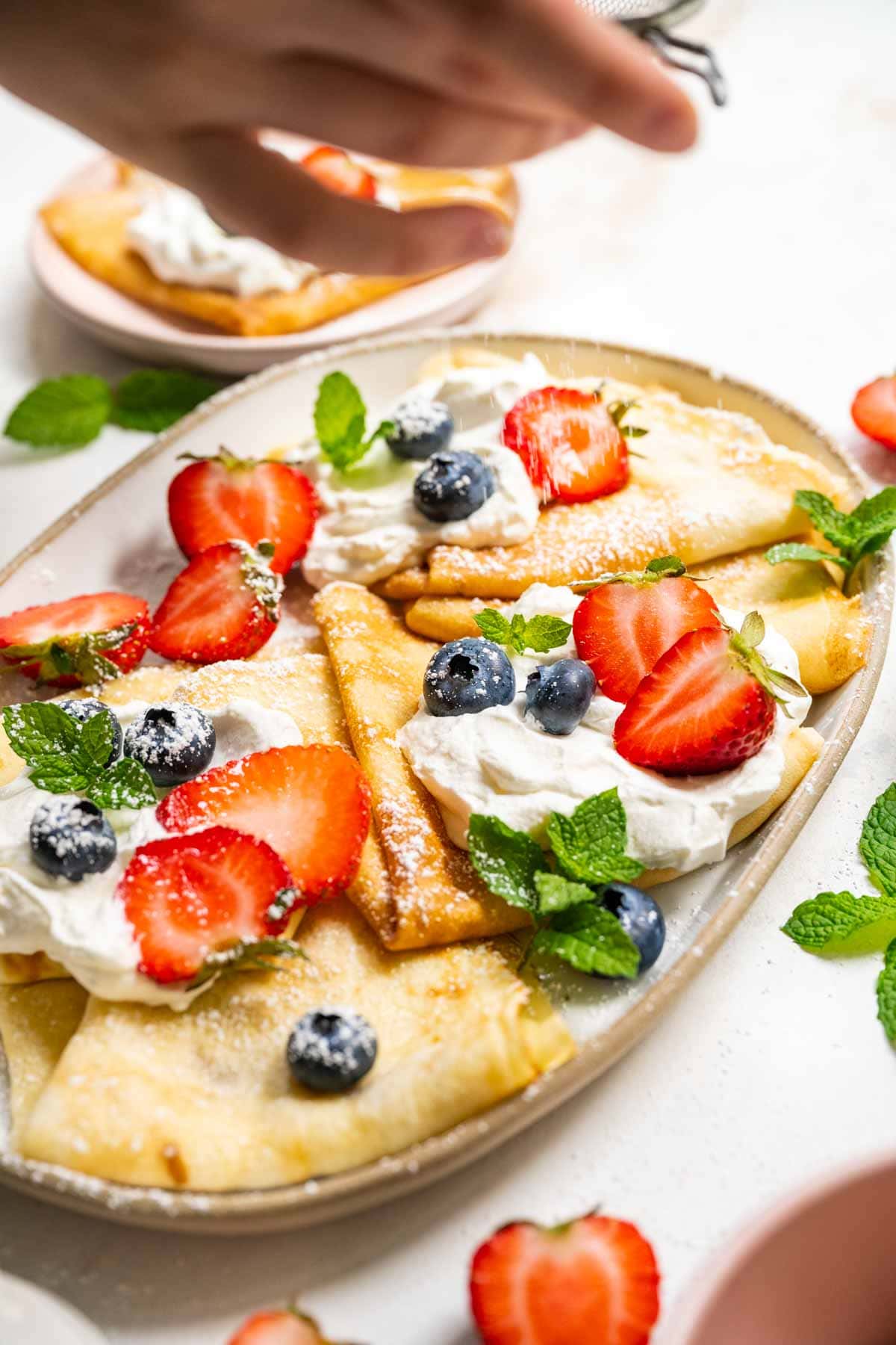 Easy Crepes on serving platter dusting with sugar