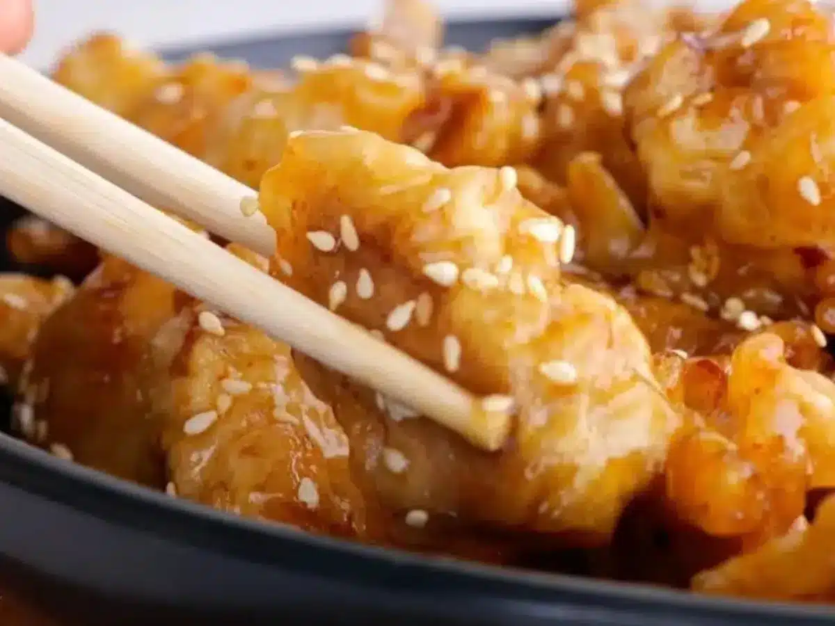 Piece of chicken picked up by chop sticks