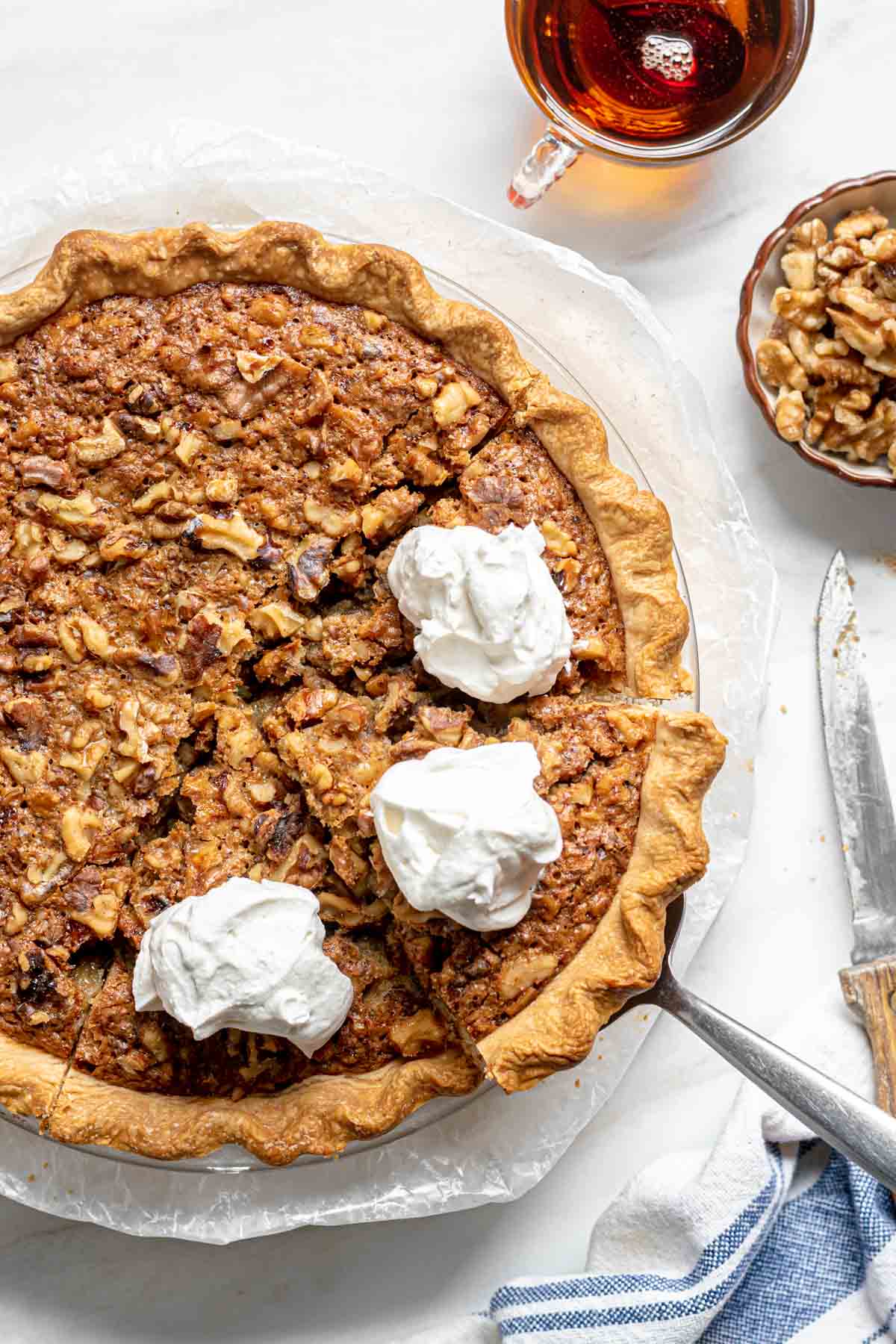 Maple Walnut Pie sliced in pie pan with whipped cream