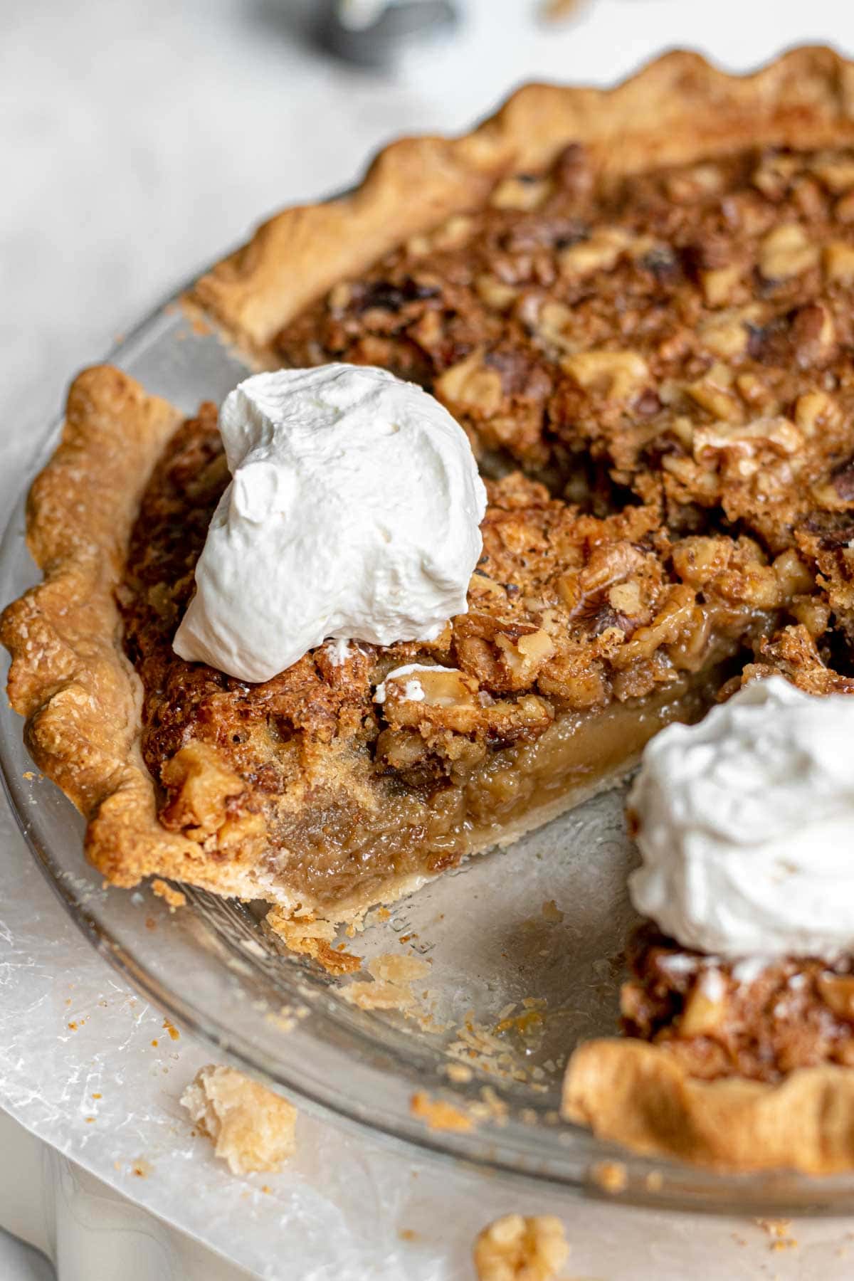 Maple Walnut Pie sliced in pie pan with whipped cream