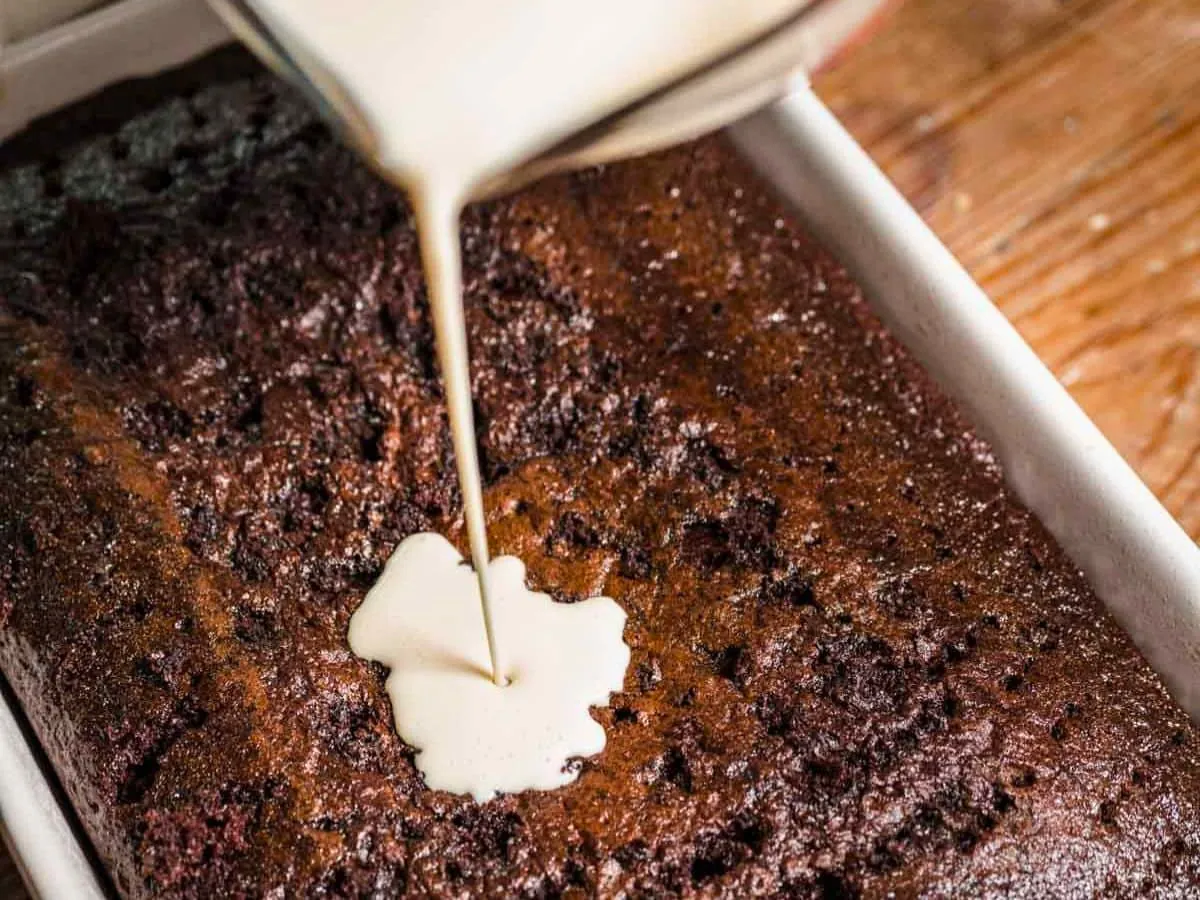 Cream being poured into chocolate cake