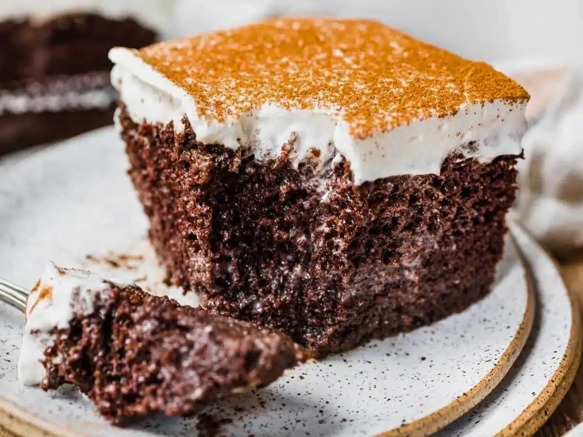 Slice of chocolate cake with fork and bite taken out on plate