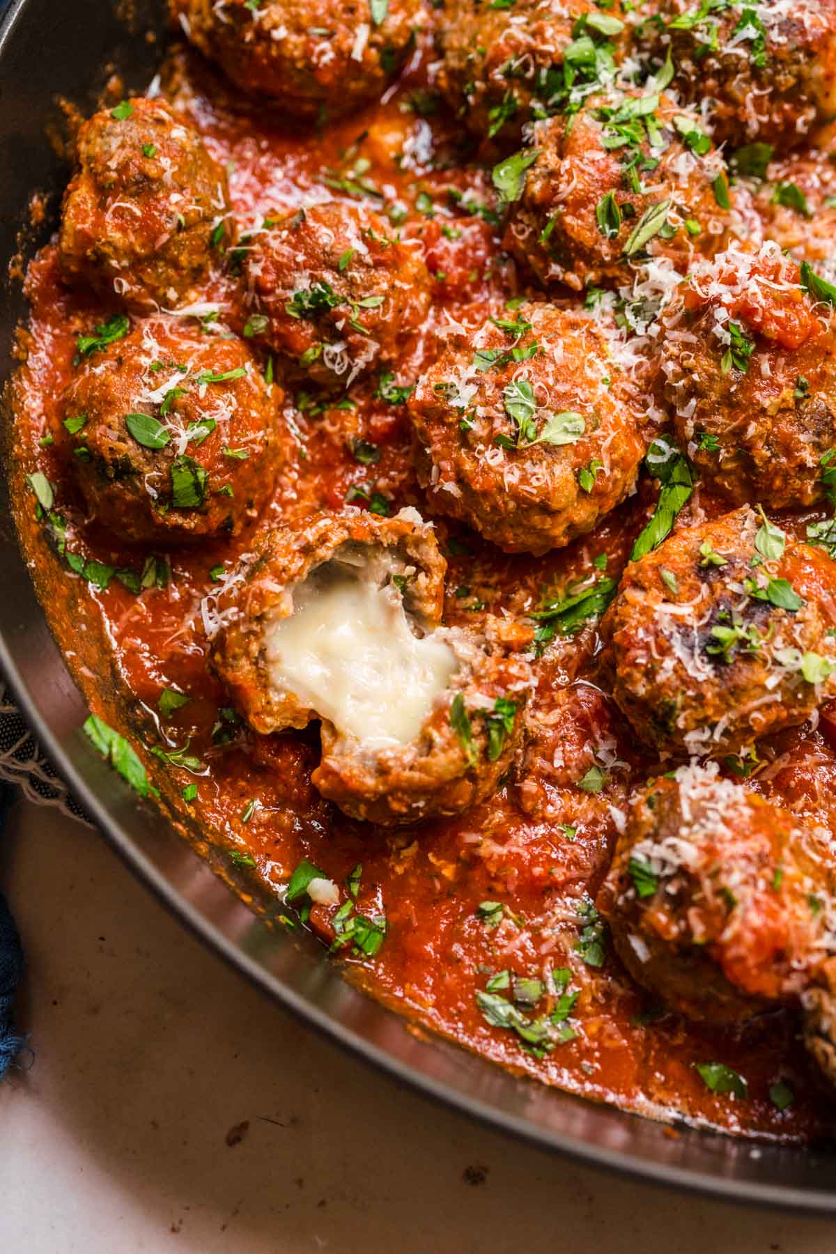 Mozzarella Stuffed Meatballs in sauce in skillet, showing melty cheese