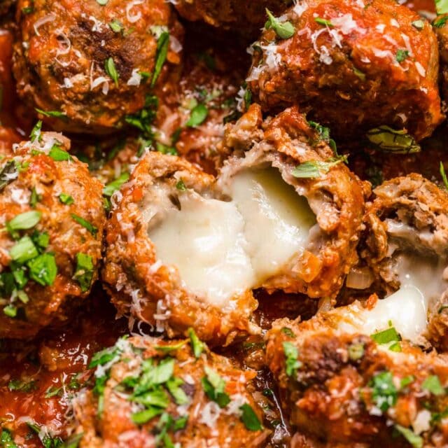 Meatballs in sauce in skillet, showing melty cheese at center 4x3
