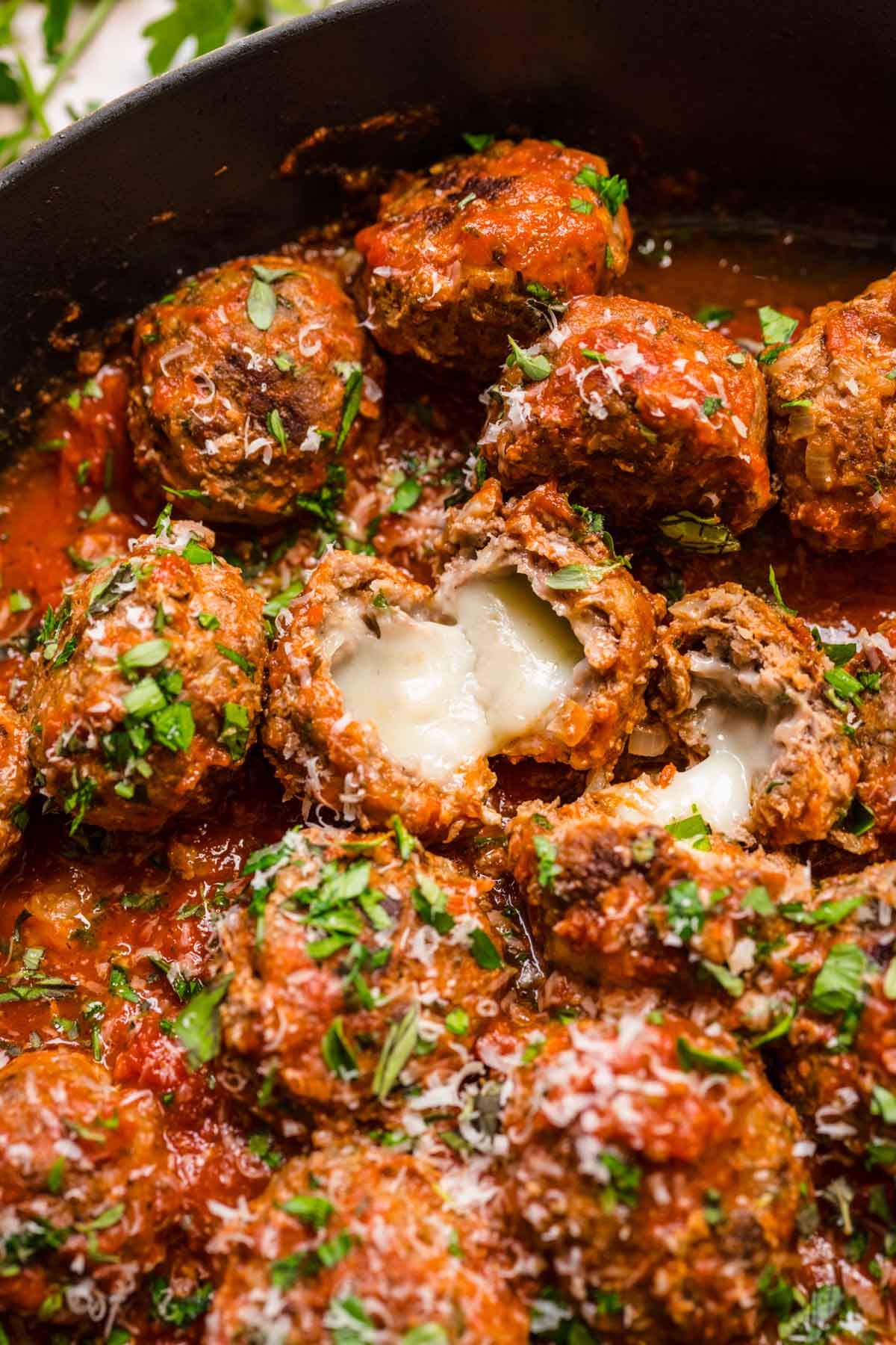 Mozzarella Stuffed Meatballs in sauce in skillet, showing melty cheese