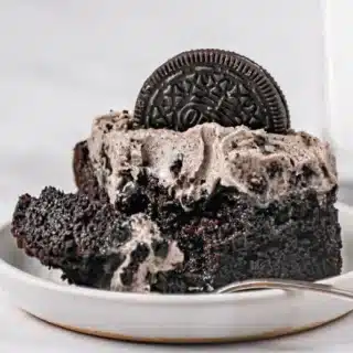 Chocolate sheet cake with icing and oreo garnish on white serving plate