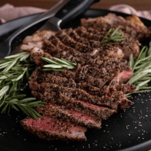 slices of medium rare meat with rosemary on a plate