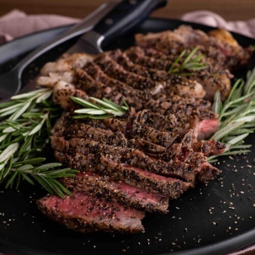slices of medium rare meat with rosemary on a plate