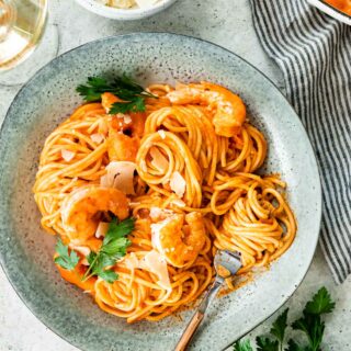 a forkful of Shrimp vodka sauce pasta garnished with fresh parsley in a bowl