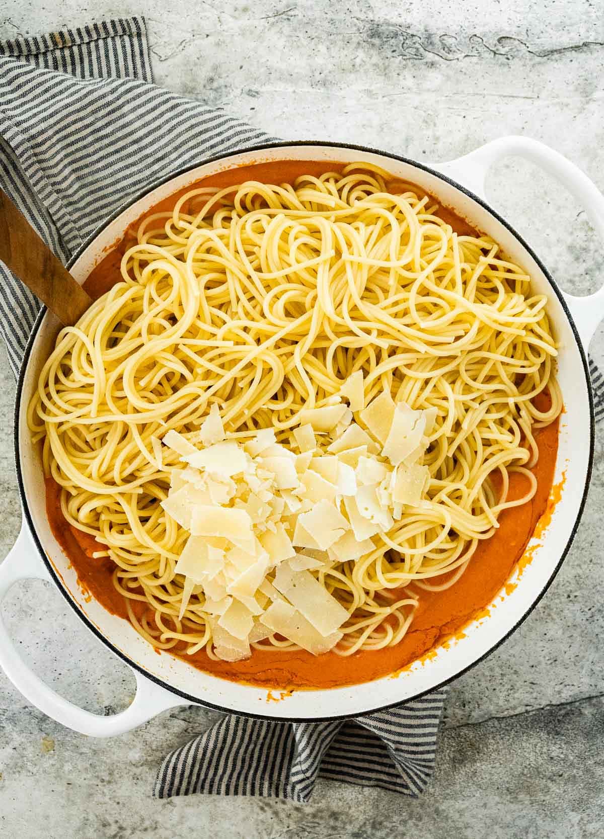 adding boiled spaghetti and parmesan to vodka sauce