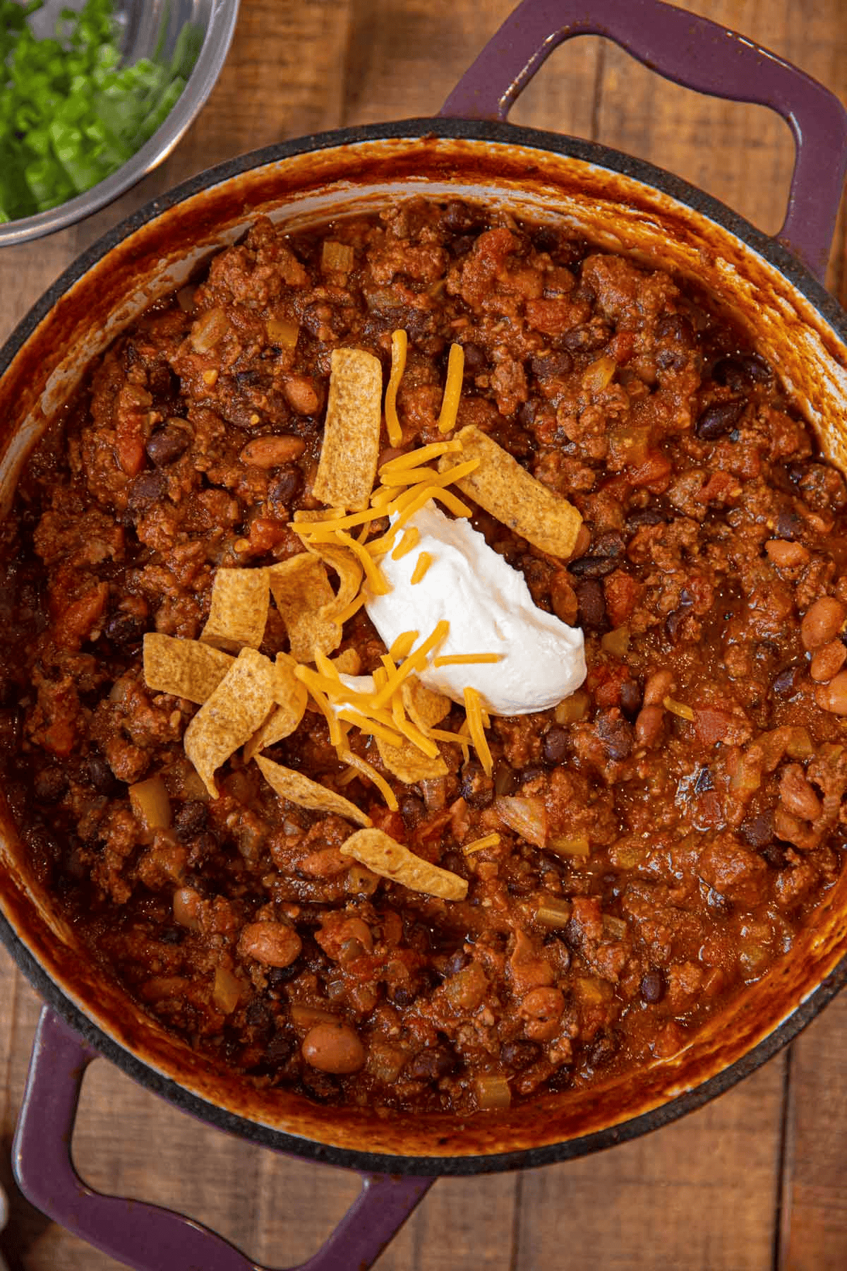 Pot of chili topped with sour cream, cheese, and tortilla strips
