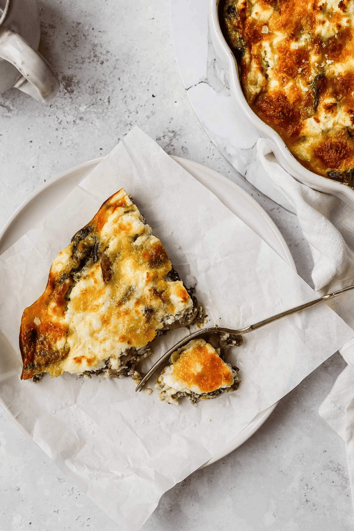 Slice of quiche with fork taking a bite out