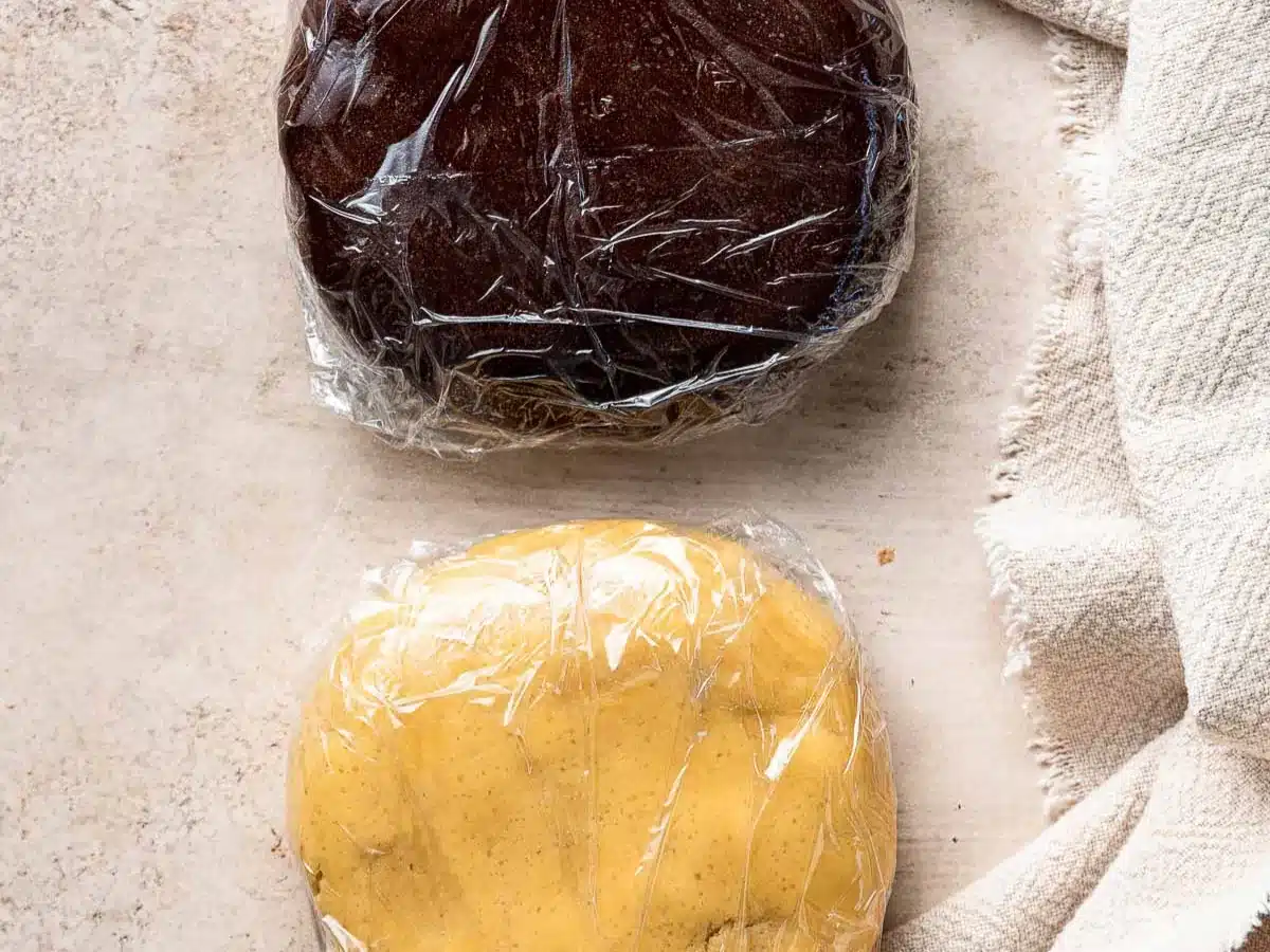 Two separate balls of dough wrapped in plastic wrap.