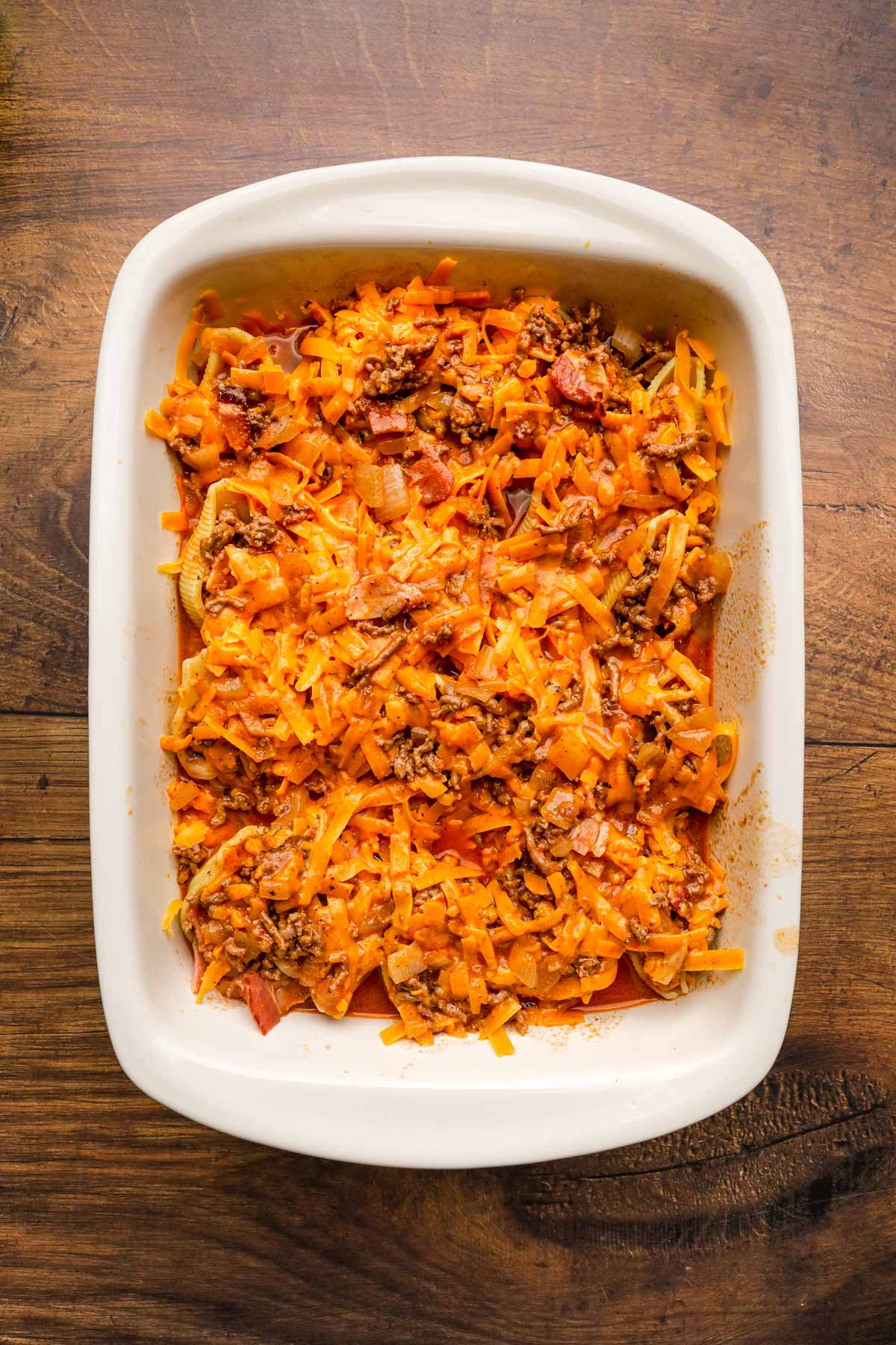 Bacon Beef Beer Stuffed Shells with cheese and sauce in baking dish before cooking