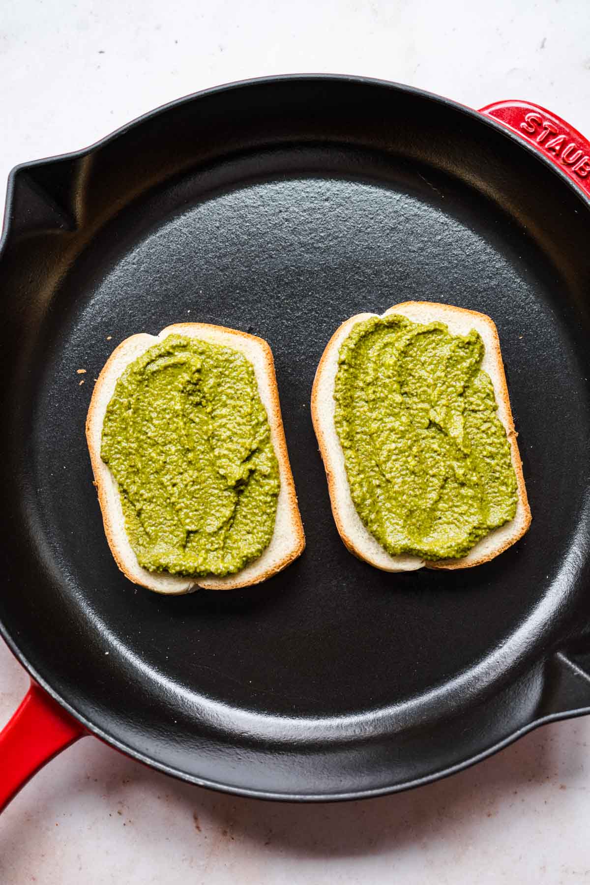 Caprese Grilled Cheese pesto added to bread in cooking pan
